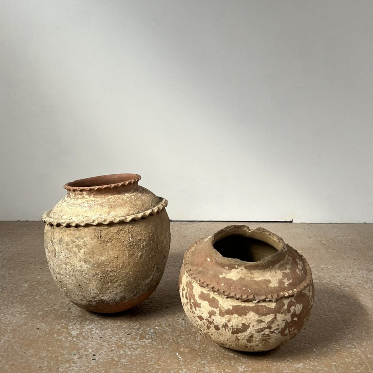 Two rustic clay pots on a neutral background