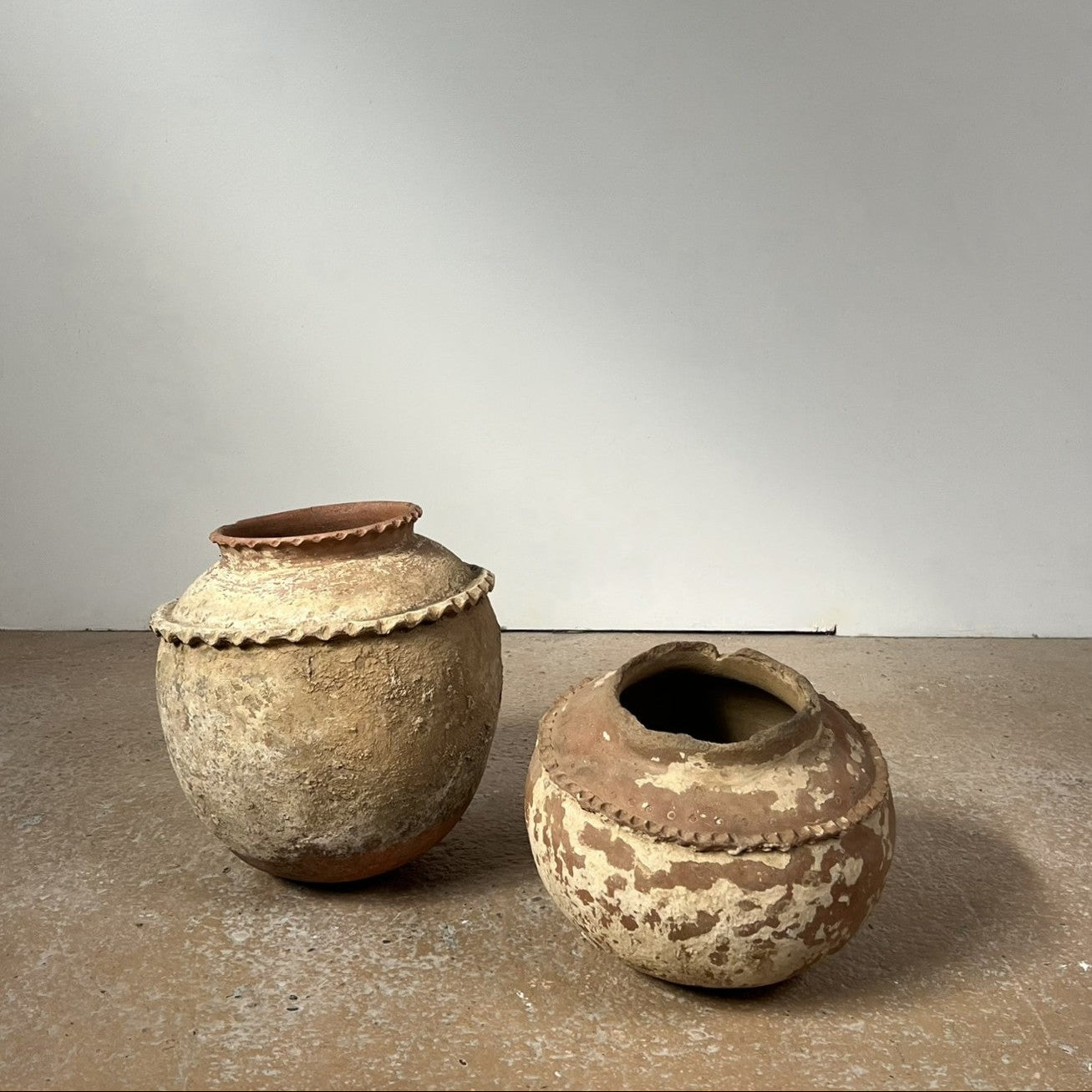 Two rustic clay pots on a neutral background