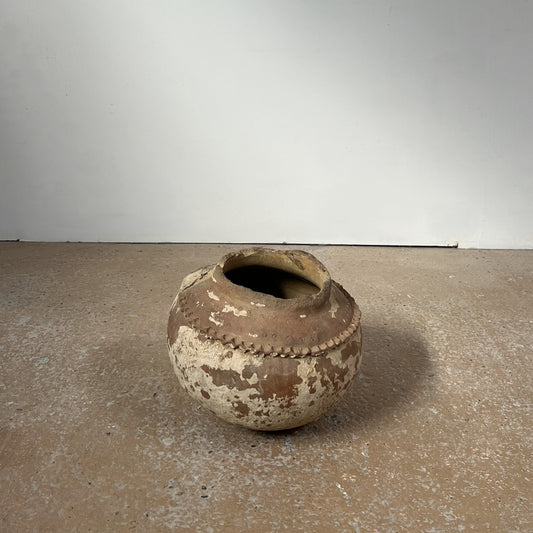 Antique ceramic pot on a concrete floor with a plain background