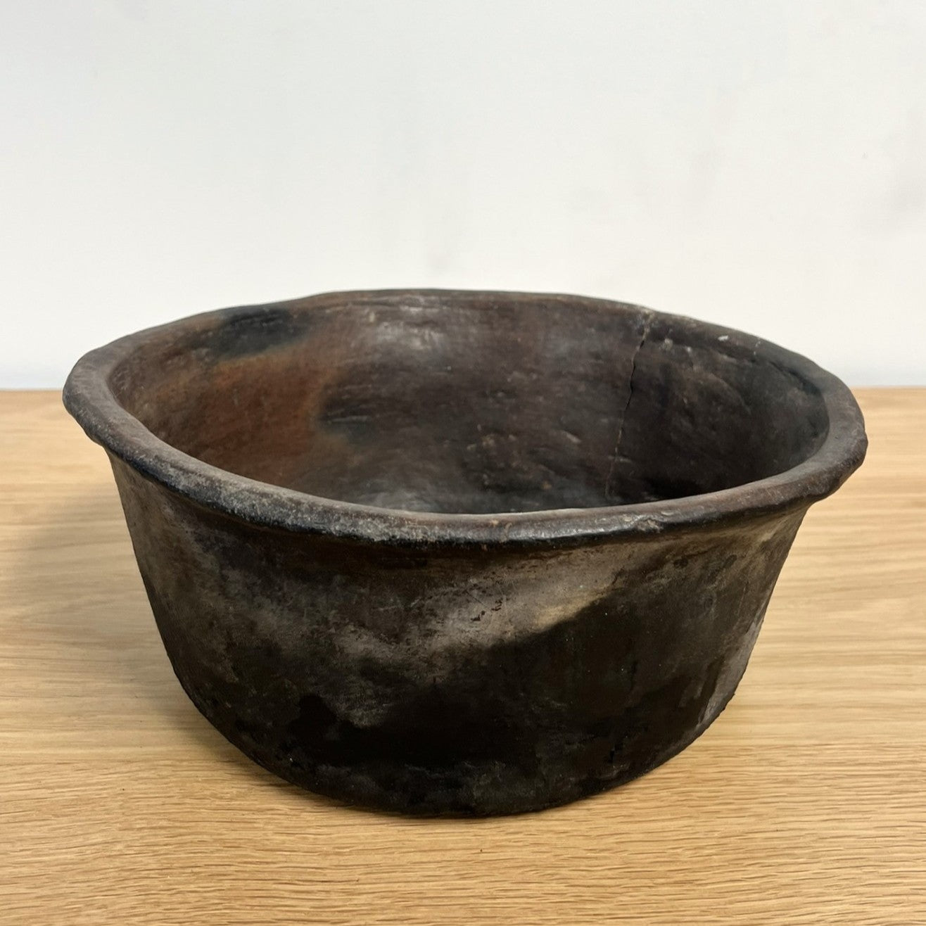 Vintage dark brown pot on a light wooden surface with a white background