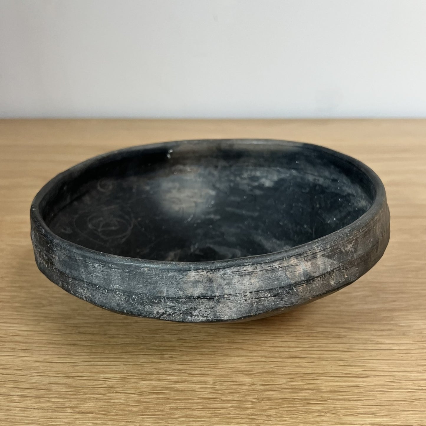 Black ceramic bowl on a wooden surface with a white background