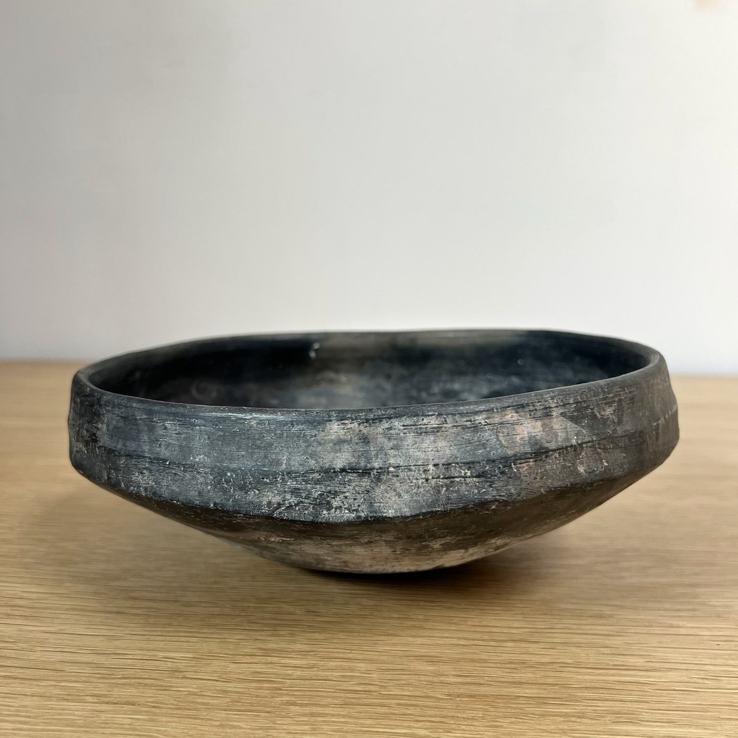Black ceramic bowl on a wooden surface with a neutral background.