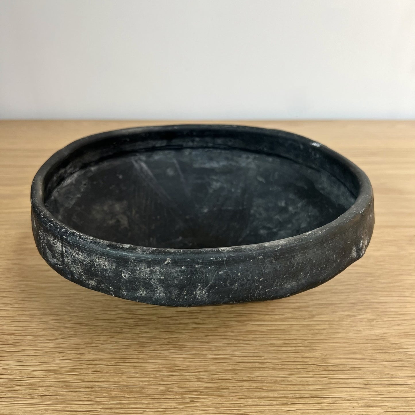 Black ceramic bowl on a wooden surface with a white background