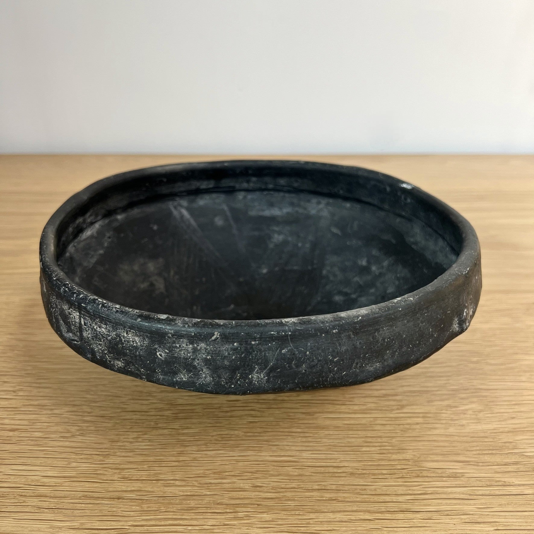 Black ceramic bowl on a wooden surface with a white background