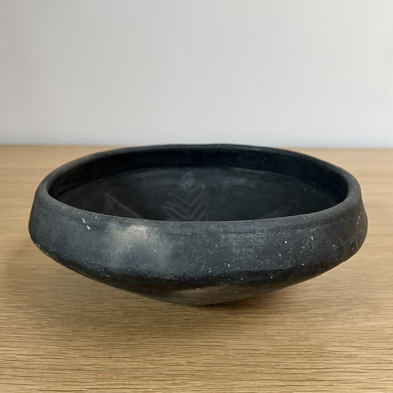 Black ceramic bowl on a wooden surface with a plain background