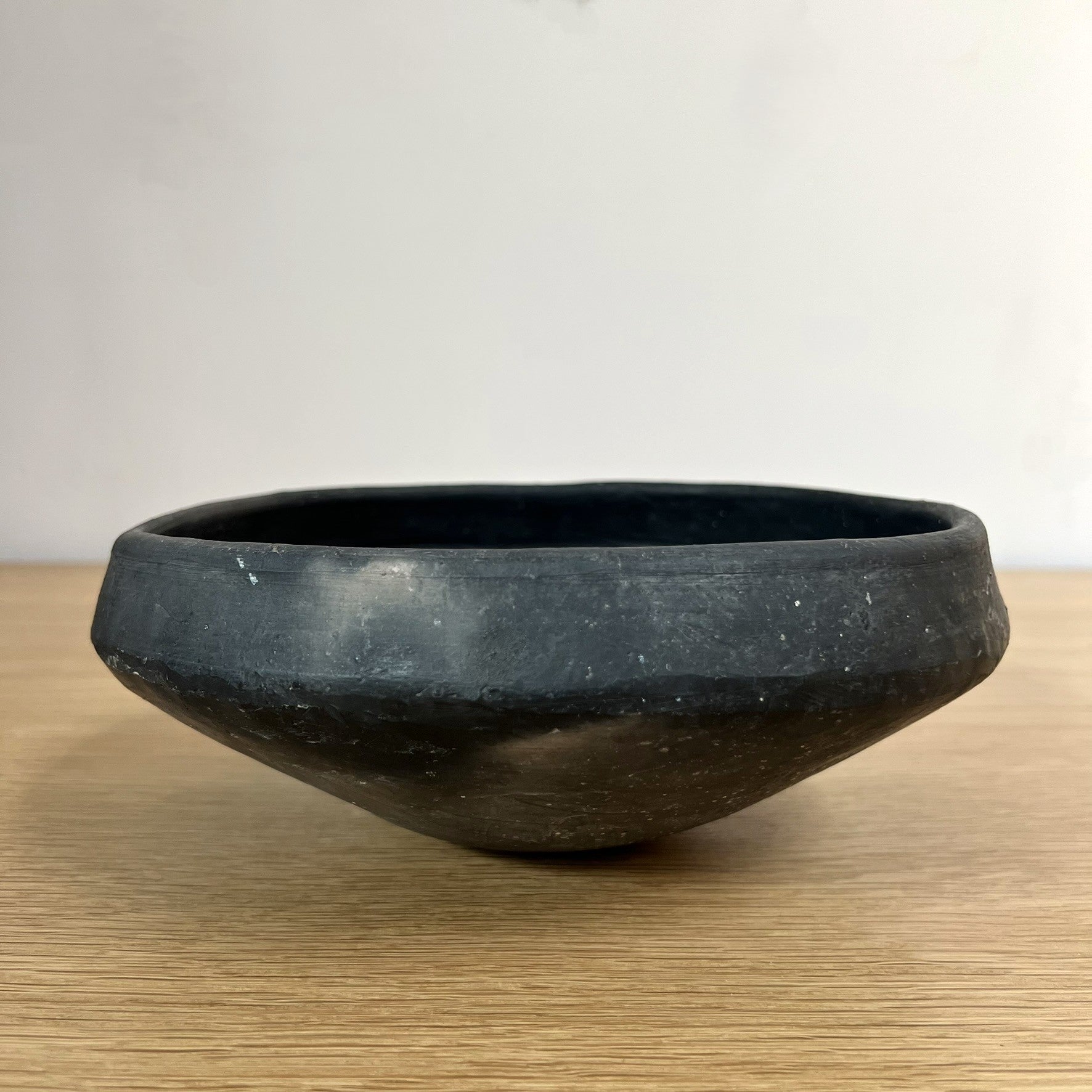Black ceramic bowl on a wooden surface with a white background