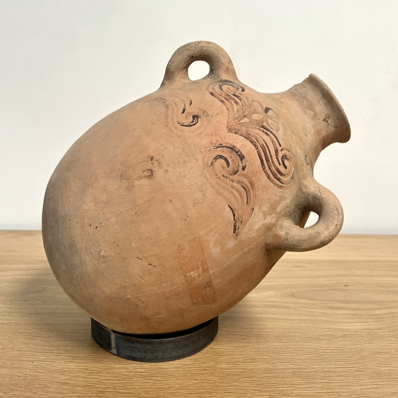 Clay pot with decorative designs on a wooden surface